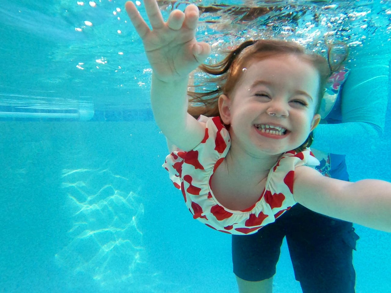 A young girl reaching forward underwater during a swim lesson