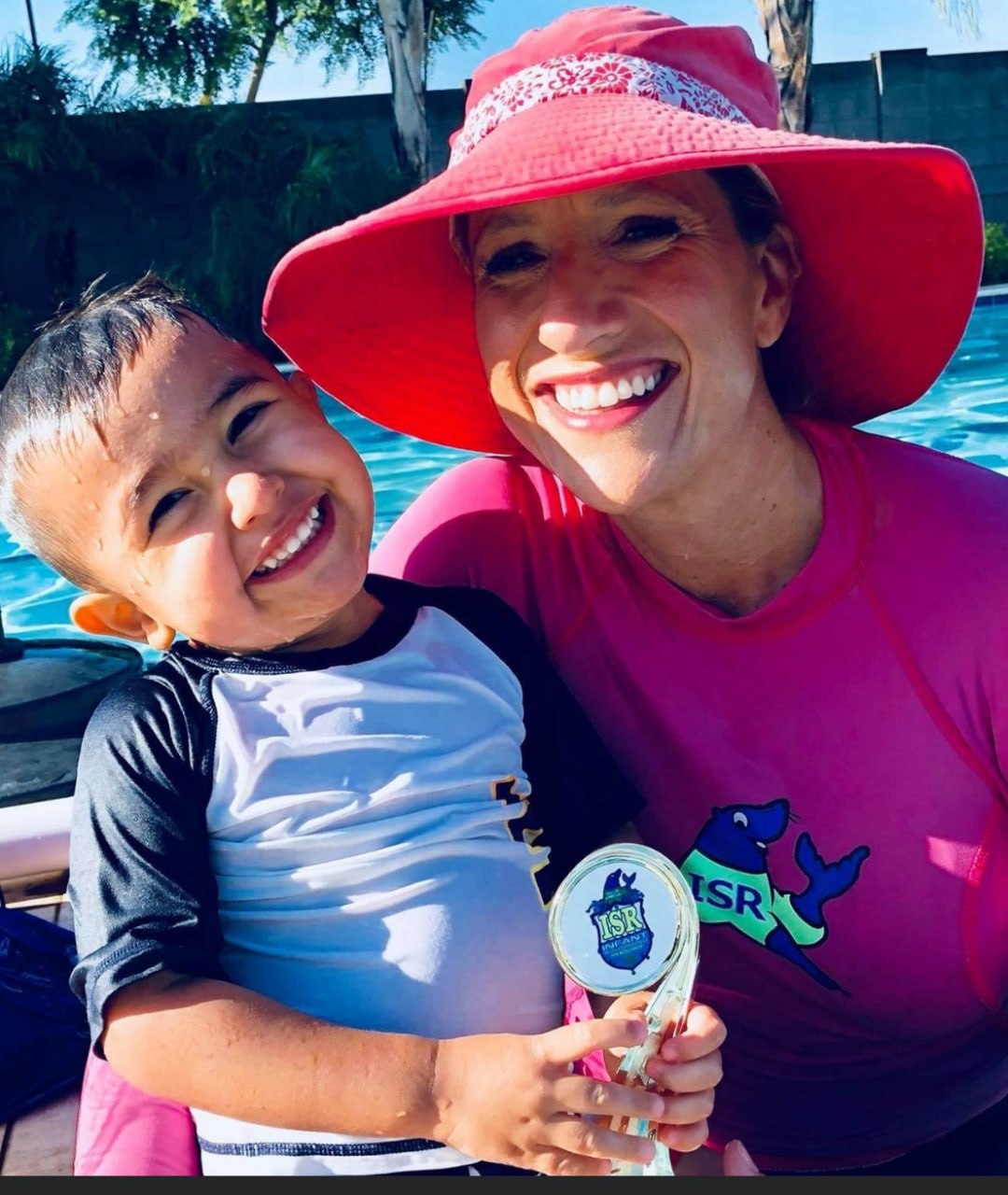 Colleen with a student holding an ISR trophy by the pool